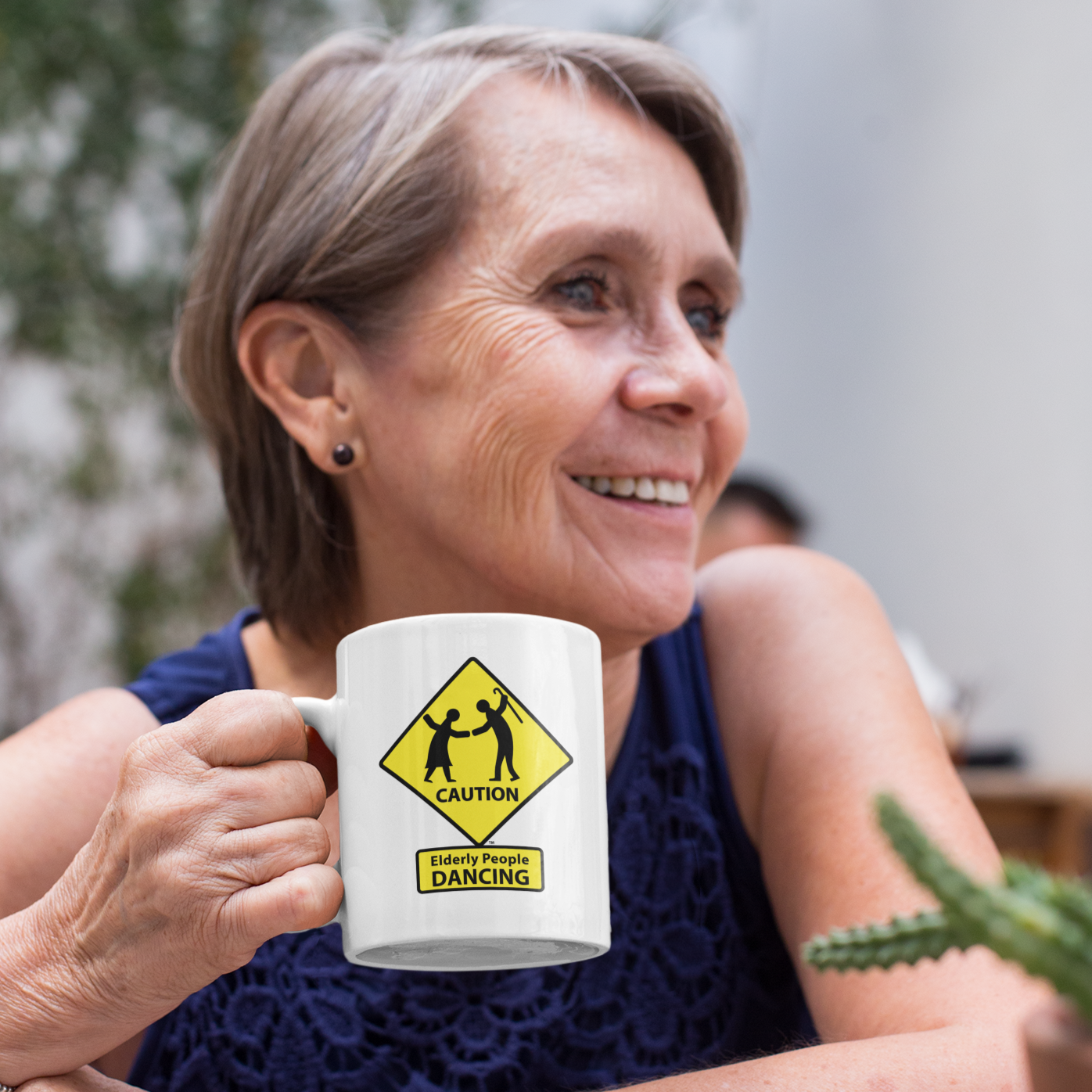 Mature woman holding a coffee cup that says "Caution: Elderly People DANCING"